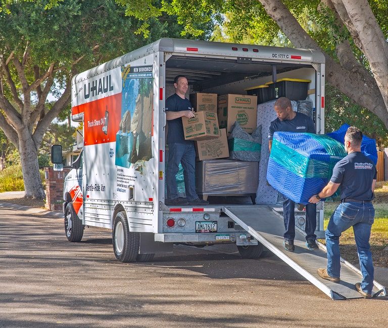 Movers loading boxes into a U-Haul truck at the storage facility